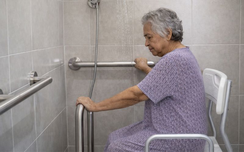 idosa utilizando barras de apoio para maior segurança no banho